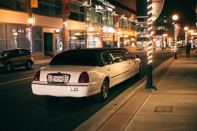 Black stretch limousine driving on a city road at dusk